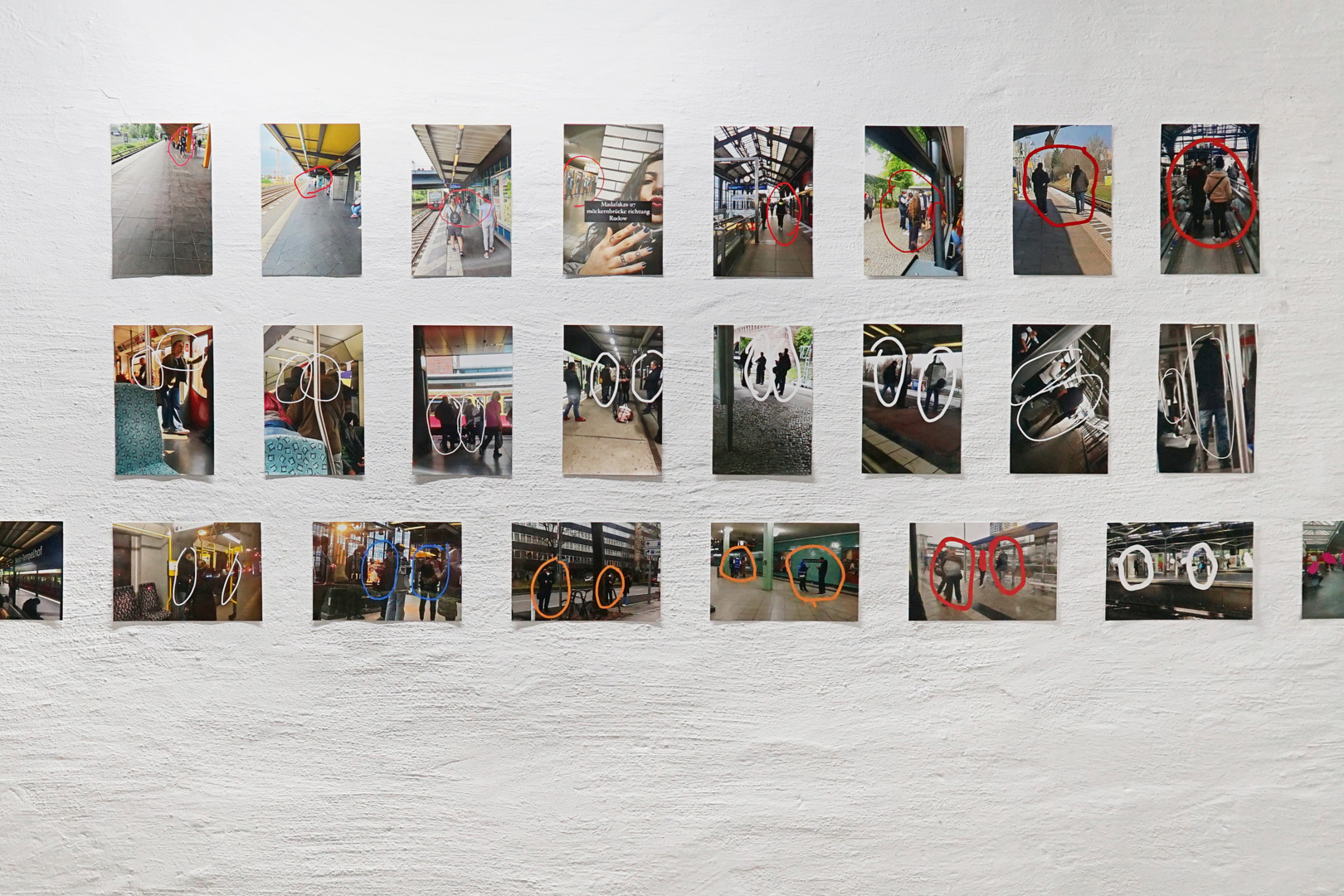 Fotos in drei Reihen untereinander an einer Wand befestigt. Darauf zu sehen Kontrollen in der Bahn, die Kontrollierenden sind mit frei gezeichneten Kringeln hervorgehoben