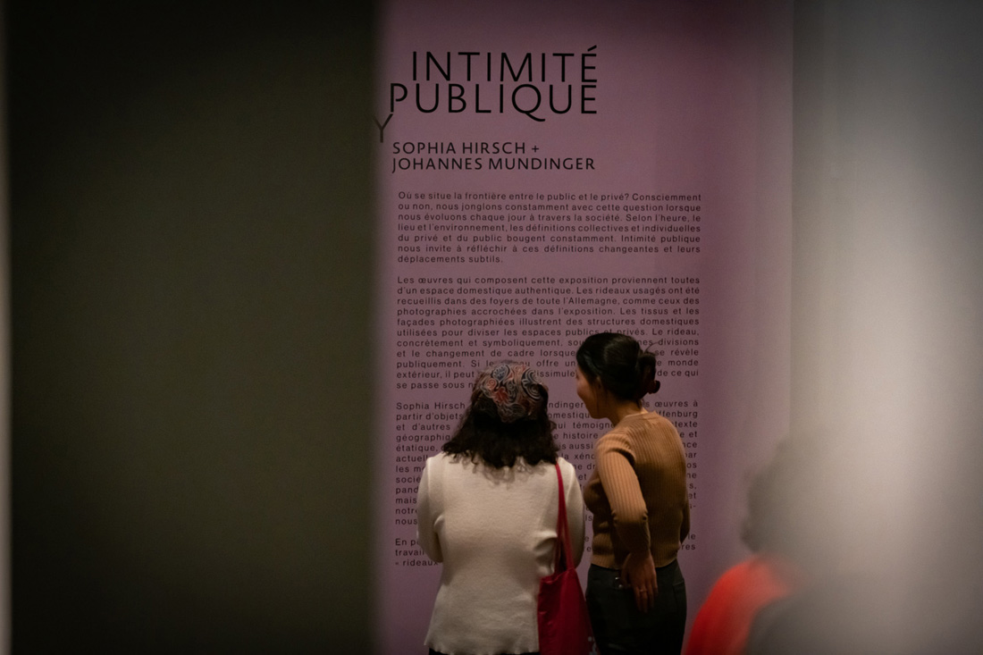 people reading an exhibition text on a wall
